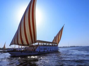 A dahabeya sails with its sail set and passengers aboard on the Nile.