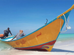 Locals navigate a colorful boat onto the beach