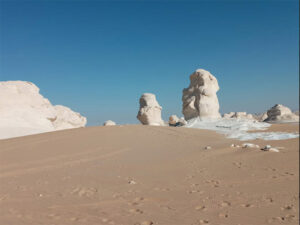 Blue sky, white stones and a large area of ​​sand in the middle.