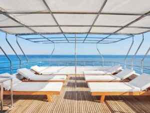 Diving Spot with Sharks – a liveaboard adventure. Here: The sun deck with various loungers, covered in white against a blue sky and sea