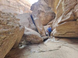 Two hikers walking through a rocky path in Gallala Mountains