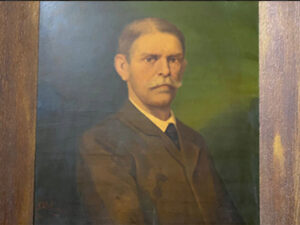 The German Georg Schweinfurth, first president of the Geographical Society, looks at the guests from a picture frame on the wall with a serious expression.