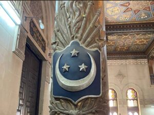 The replica of the Egyptian flag of the time, a coat of arms on a green background with a crescent moon and three stars, hangs as decoration on a column in the Geographical Society.