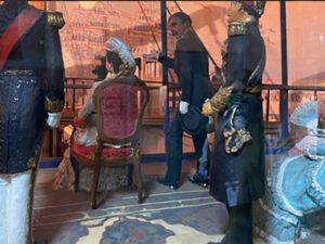 Lifelike recreated scene of the opening of the Suez Canal as a puppet show with music and moving images. Detailed in clothing and arrangement.