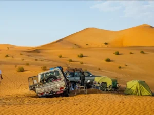 Camping site with tents and off road vehicles in the vast dunes of Oman's Empty Quarter desert