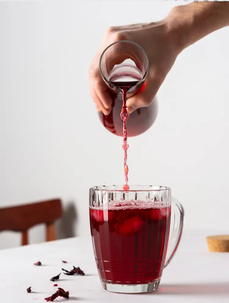 Red juice poured from glass jar into a glass