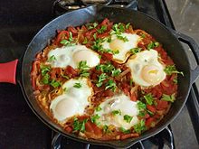 Eggs in a pan in a bed of tomatoe sauce