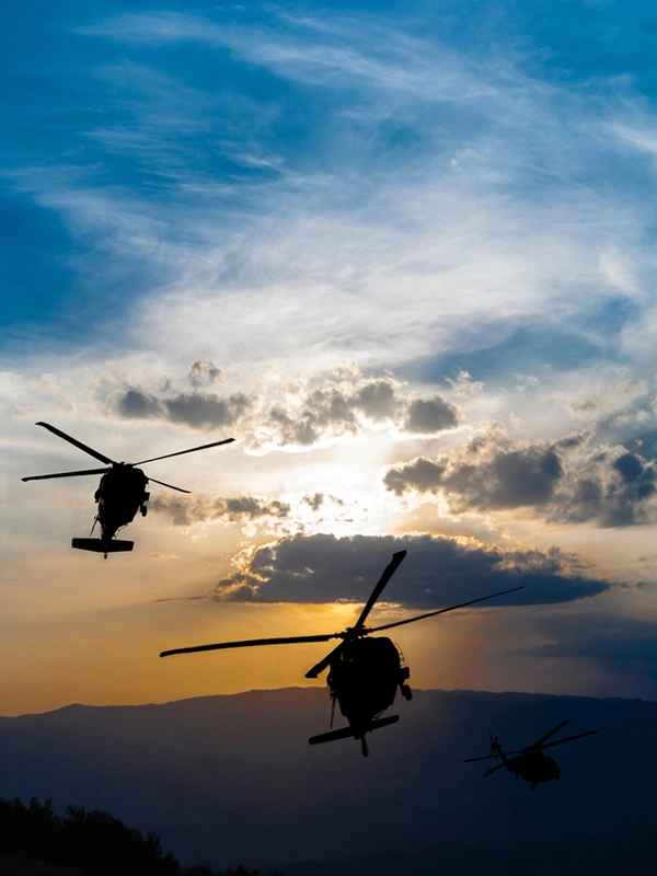 Silhouette of two helicopters in the sky while sun down