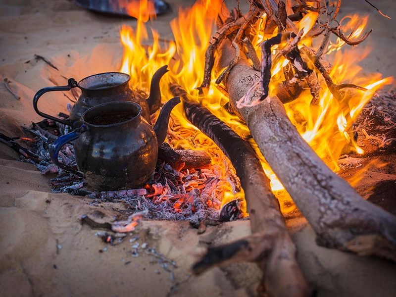 Schwarze Teekannen auf Holzkohle Teekanne auf dem Lagerfeuer
